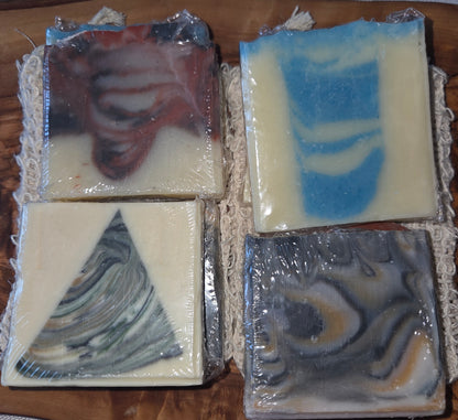 Four wrapped bars of soap with marbled patterns on a wooden surface. Comes with a sisal bag.