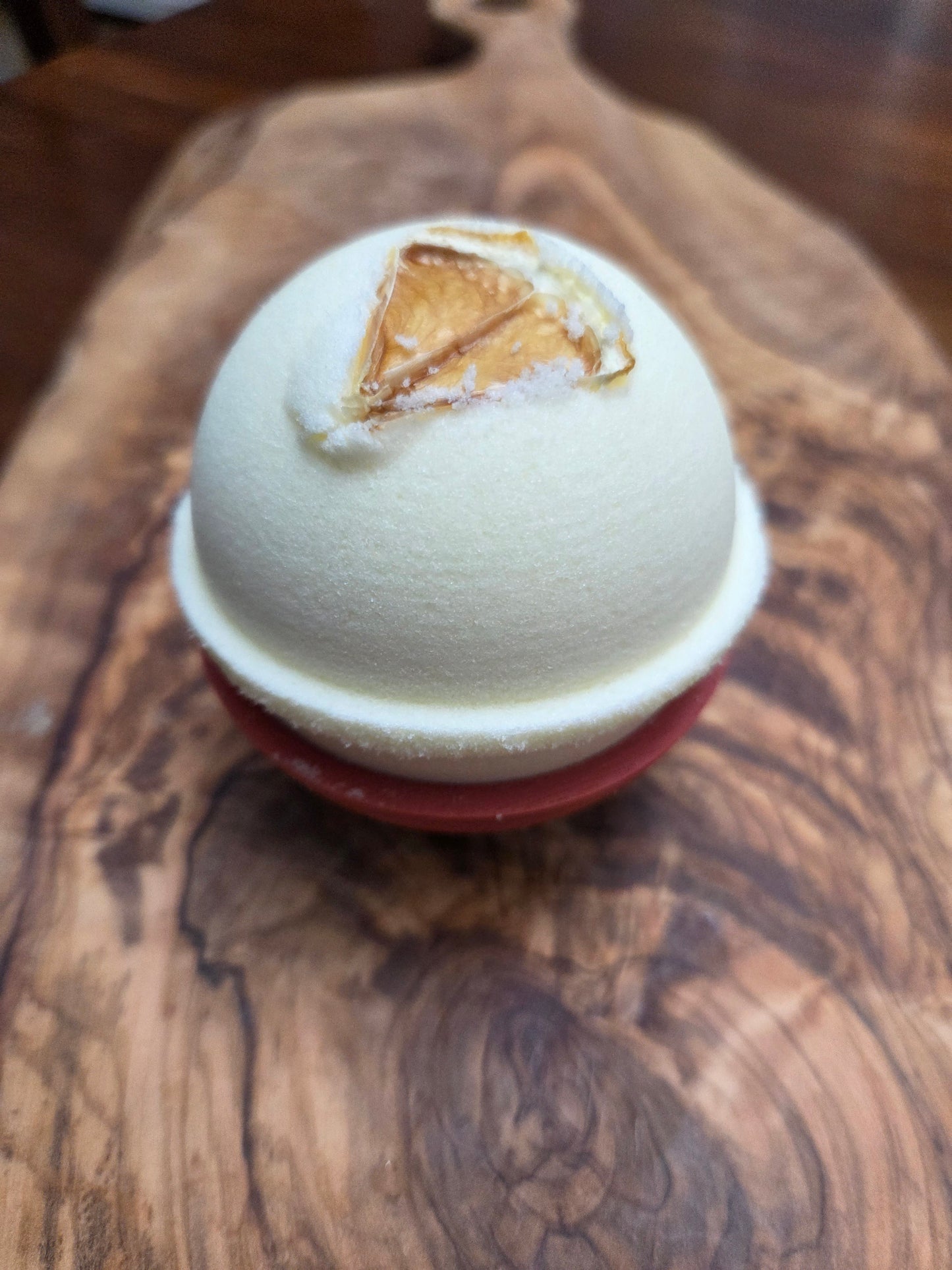 Light Yellow Bath bomb  in Lemon essential oil scent with 1-
/4 lemon slice on a wooden surface